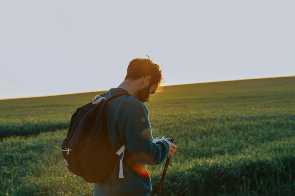 Homem de mochila em um campo verde