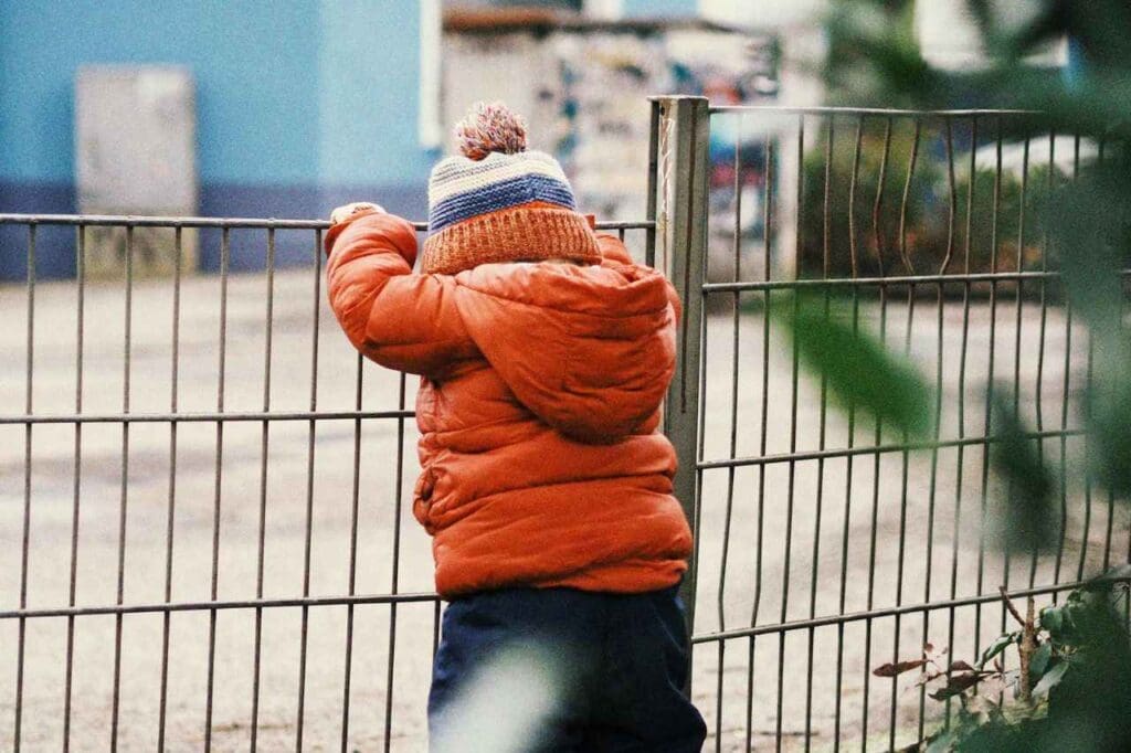 Criança apoiada em portão