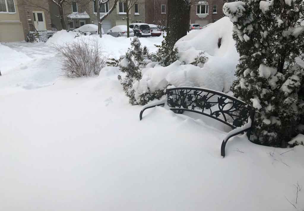 Foto de um banco preto coberto de neve.