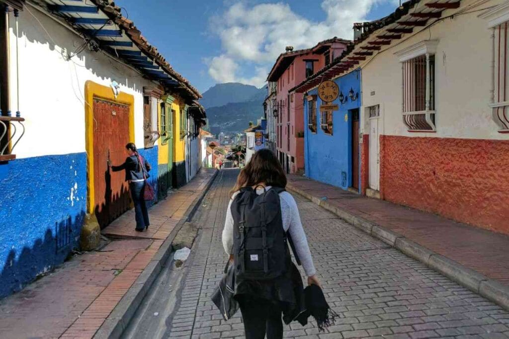 Foto de uma pessoa andando em uma rua com casas coloridas