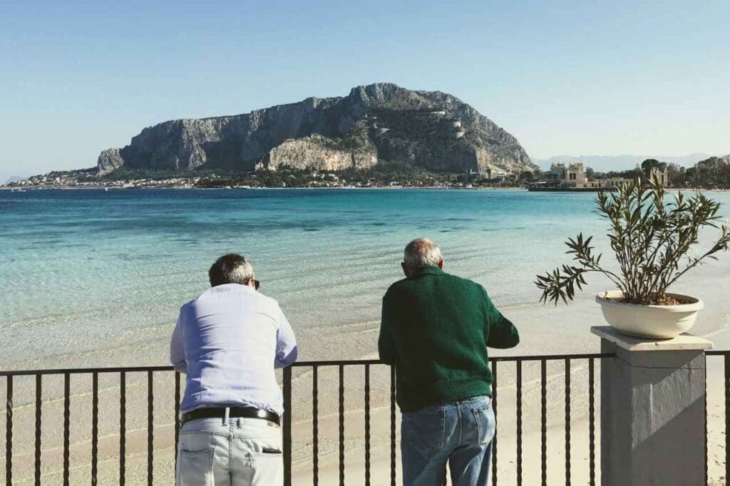 Foto de dois homens de costas admirando uma praia