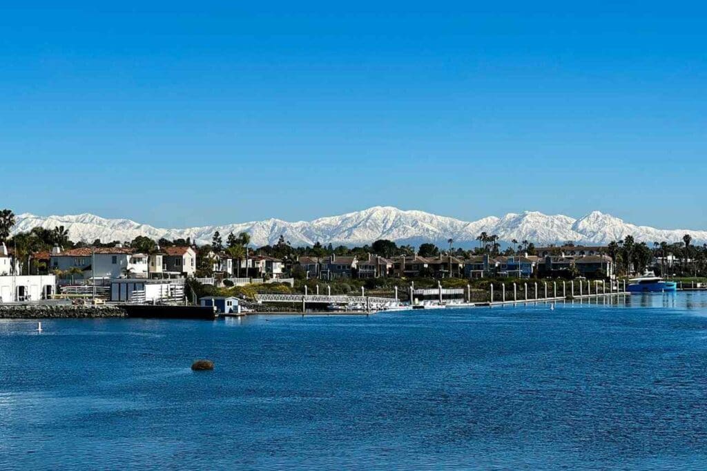 Foto do litoral de uma cidade com montanhas ao fundo