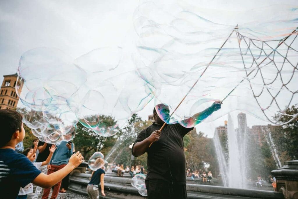 Foto de homem fazendo bolhas de sabão com crianças