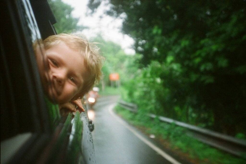Foto de criança com a cabeça para fora da janela do carro