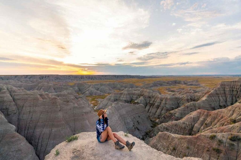 Foto de uma mulher sentada em uma pedra em uma paisagem com várias montanhas