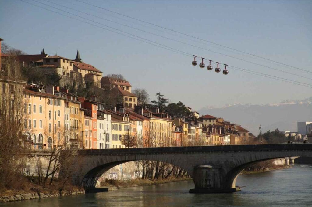 Foto de um teleférico passando por uma ponte sobre um rio